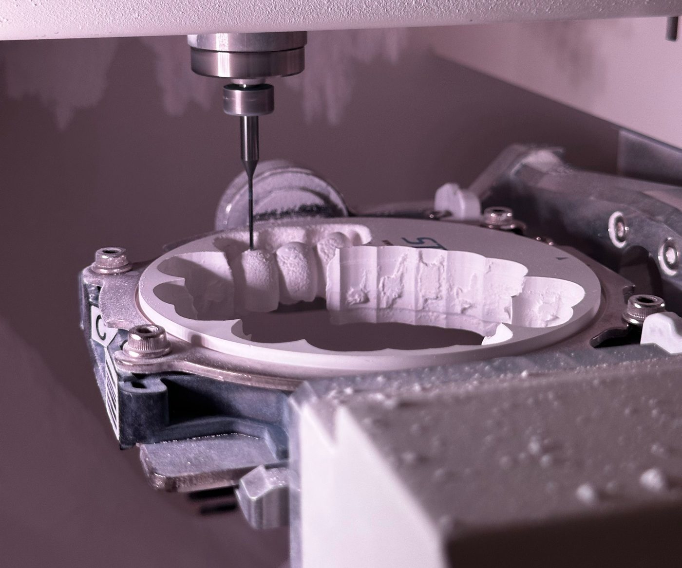 A five-axis mill cutting a full arch from a zirconia disc