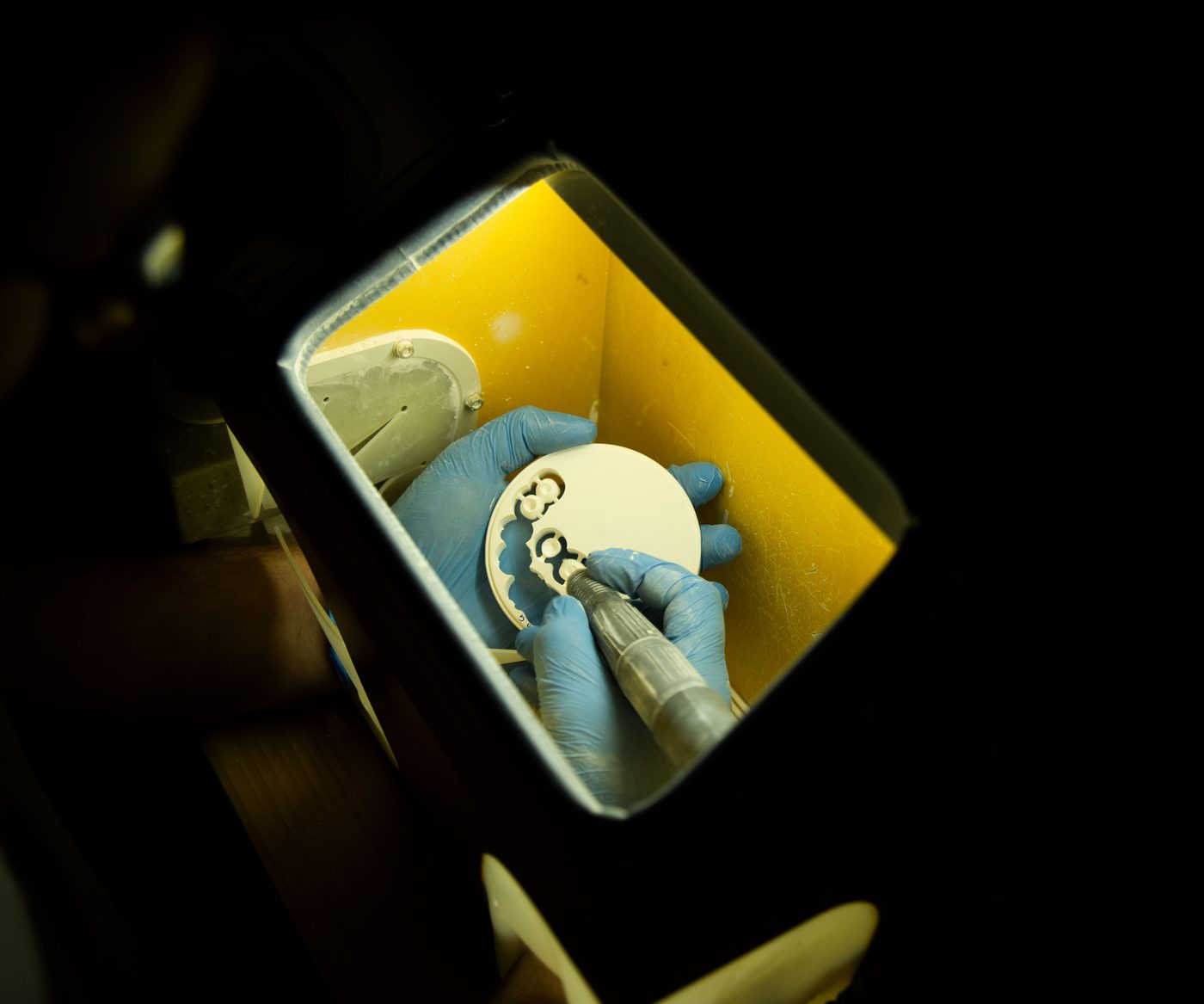 A technician working on a milled disc under a bench lamp