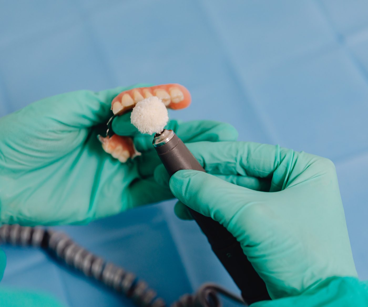 A technician polishing a partial denture with a handpiece